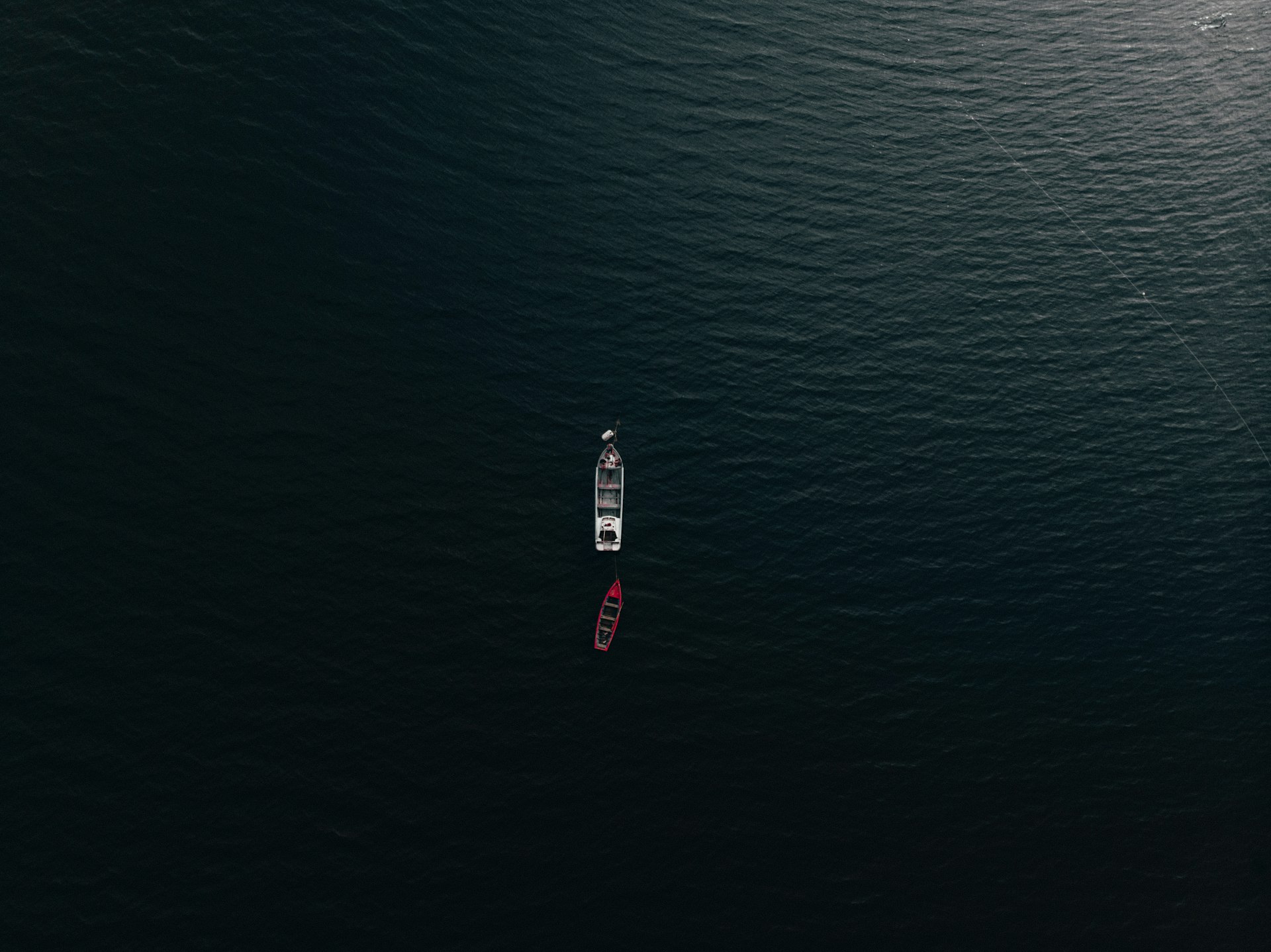 Aerial view of two vessels being relocated across dark coastal waters